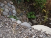 Pitoresc: bolovani multicolori de râu zidiți la un podeț improvizat peste un mic pârâu